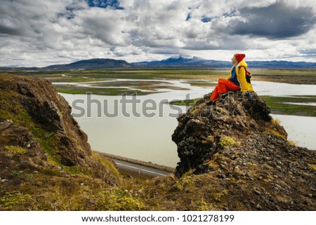 Happy young woman in bright clothes traveling Iceland, enjouing nature