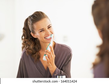 Happy Young Woman Brushing Teeth In Bathroom