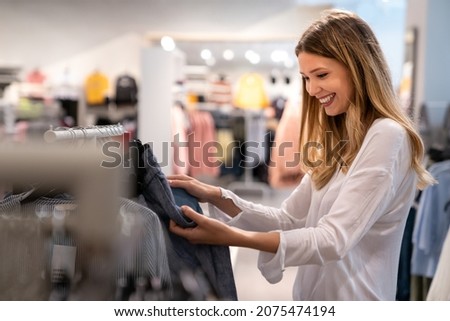 Happy young woman buying new clothes in store. Sale shopping fashion and people concept