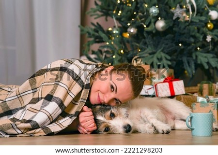 Happy young woman at the Christmas tree with her dog.
