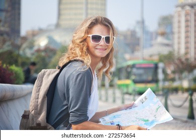 happy young woman with a city map and a backpack smiling