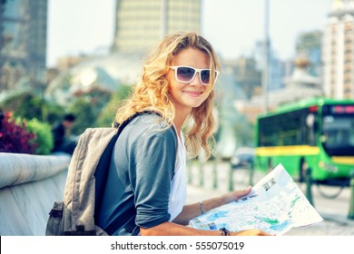 happy young woman with a city map and a backpack smiling - Powered by Shutterstock