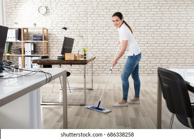 Happy Young Woman Cleaning The Floor With Mop In Modern Office