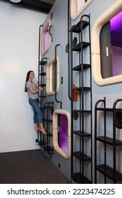 Happy Young Woman Climbing Up Ladder To Capsule In Pod Hostel