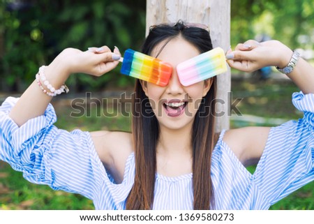 Happy young woman with colorful ice cream in hands in garden. Lifestyle and relaxing concept.