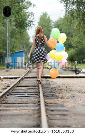 Happy young woman with colorful latex balloons, outdoors