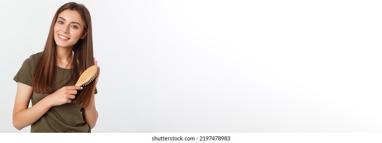 Happy young woman combing her long healthy hair on white background.