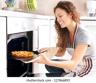 Happy Young Woman Cooking Pizza At Home. Oven