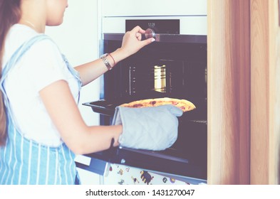 Fröhliche junge Frau, die zu Hause Pizza kocht