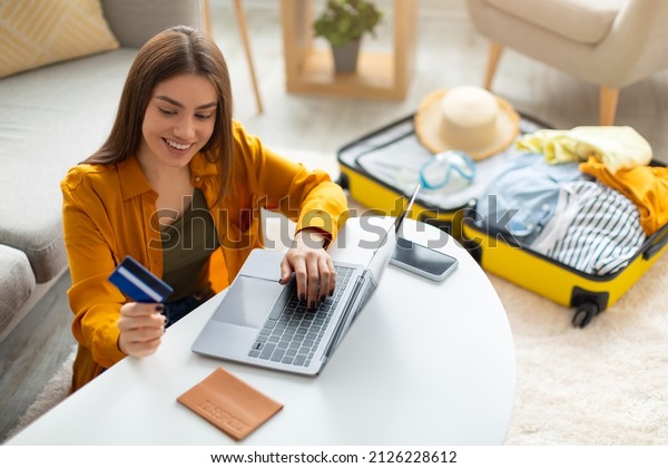 Happy young woman with\
credit card booking vacation at travel agency or making hotel\
reservation online, using laptop computer, planning abroad trip at\
home, copy space