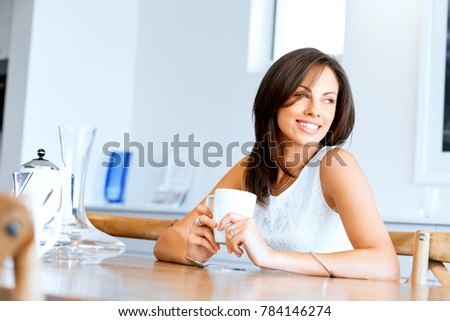 Happy young woman with cup of tea or coffee at home