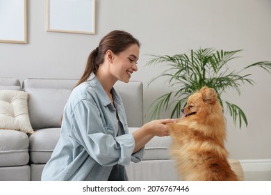 Happy Young Woman With Cute Dog In Living Room