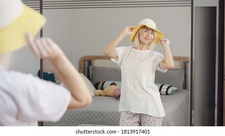 Happy young woman is dancing in the bedroom. Woman makes funny dance moves at home while having fun with the hat. - Shutterstock ID 1813917401