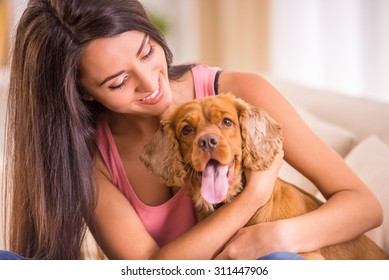 Happy young woman with dog are sitting on sofa.