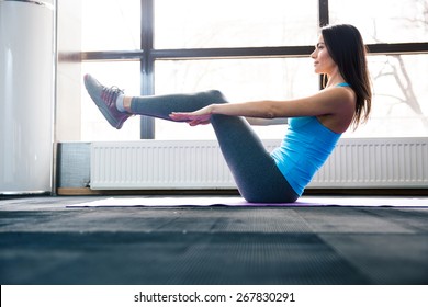 Happy young woman doing exercise on yoga mat at gym