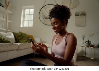 Happy Young Woman Doing Yoga And Using Cell Phone Sitting On The Floor