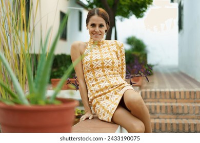 Happy young woman in dress sitting near aloe vera plant in daylight - Powered by Shutterstock