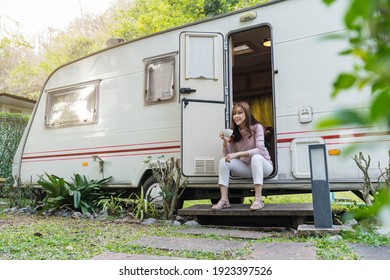 happy young woman drinking coffee at door of a camper RV van motorhome - Shutterstock ID 1923397526