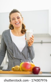 Happy Young Woman Drinking Smoothie In Kitchen