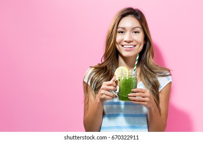 Happy Young Woman Drinking Smoothie On A Solid Color Background