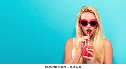 Happy Young Woman Drinking Smoothie On A Solid Background