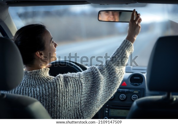 Happy young woman\
drives a car, inside\
view.