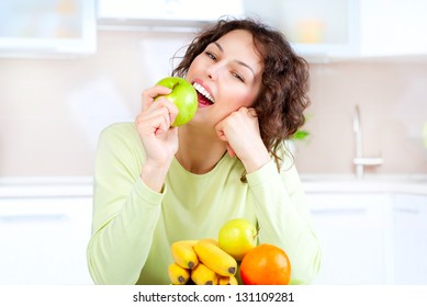 Happy Young Woman Eating Apple On Kitchen. Diet. Dieting Concept. Healthy Food