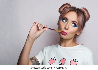 Happy Young Woman Eating Gummy Candy. Beauty Fashion Model Girl With Two Pink Bun Hairstyle And Colourful Make-up Isolated On White, Grey Background