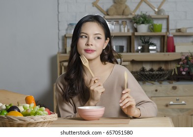 Happy Young Woman Eating Soup In Kitchen