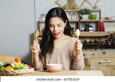 Happy Young Woman Eating Soup In Kitchen