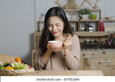 Happy Young Woman Eating Soup In Kitchen