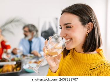 Happy young woman enjoying dinner party with family at home. Side view portrait of cheerful beautiful female toasting white wine - Powered by Shutterstock