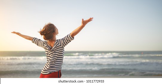happy young woman enjoying freedom with open hands on sea