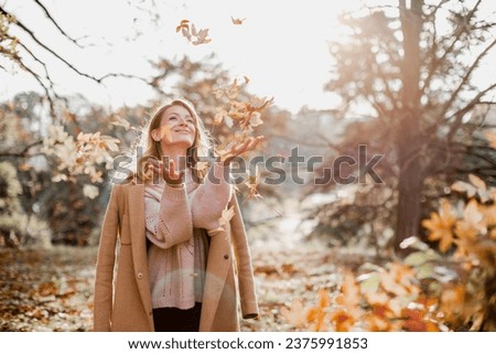 Happy young woman enjoying golden autumn on a warm sunny day. Beautiful portrait of a Caucasian girl in an autumn coat walks on a warm sunny day in the autumn park.
