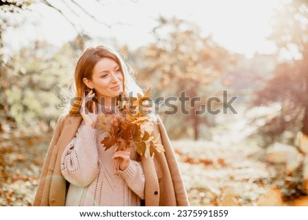 Happy young woman enjoying golden autumn on a warm sunny day. Beautiful portrait of a Caucasian girl in an autumn coat walks on a warm sunny day in the autumn park. 