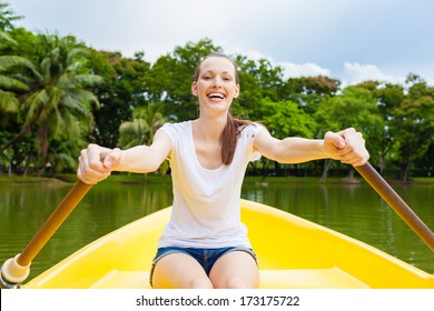 Happy young woman enjoying rowing boat ride on the lake