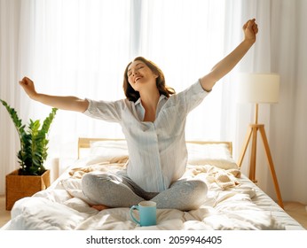 Happy young woman enjoying sunny morning on the bed.  