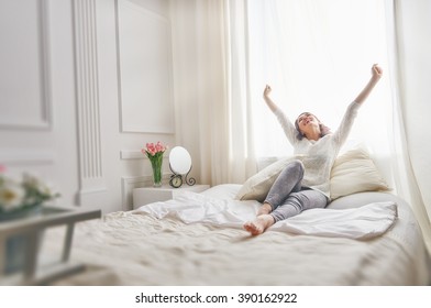 Happy young woman enjoying sunny morning on the bed 