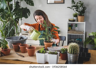 A happy young woman enjoys time at her homegarden. She is watering a plant with a watering can. - Powered by Shutterstock