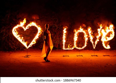 Happy Young Woman In Front Of Burning Fire Letters Love And Heart. Valentine's Day.