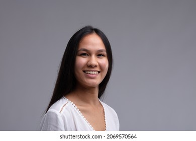 Happy Young Woman With A Genuine Warm Friendly Smile In A Head And Shoulders View On Grey