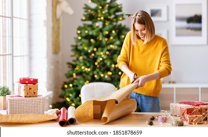 Happy Young Woman Gets Ready For Christmas And Wrapping A Gift
