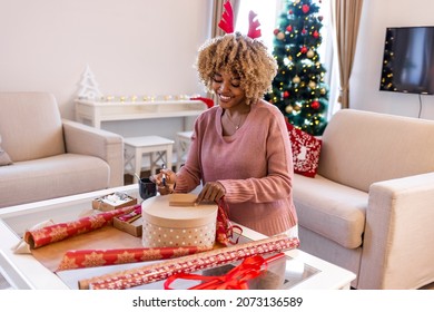 Happy young woman gets ready for christmas and wrapping a gift. Beautiful young woman wrapping Christmas gifts at home.  Christmas or New year DIY packing Concept. Step by step - Powered by Shutterstock