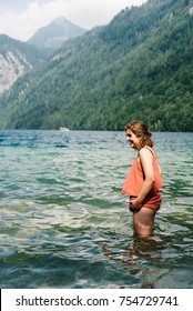 Happy Young Woman Getting Dressed Into The Water At Beautiful Lake, Konigssee,  In The Alps. Concept Fun. Space For Copy