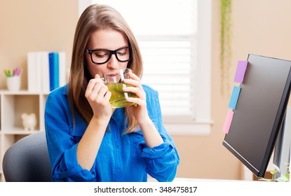 Happy Young Woman In Glasses In Her Home Office With A Cup Of Green Tea