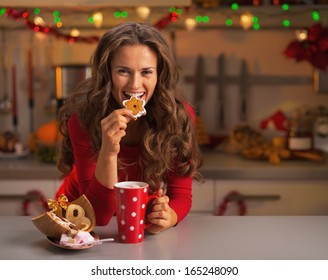 Happy Young Woman Having Eating Christmas Cookies In Kitchen