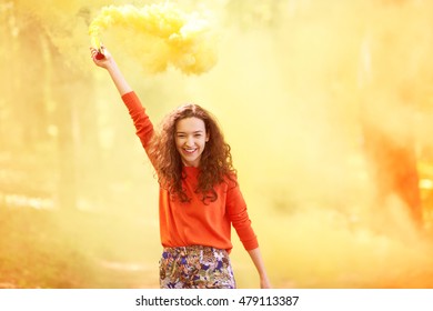 Happy Young Woman Having Fun With Colorful Powder Cloud. Girl Running With Yellow Color Smoke Bomb