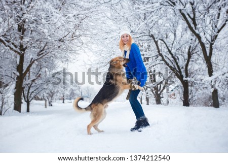 Happy young woman having fun and  playing on snowy winter walk with the dog. German shepherd. Friendship