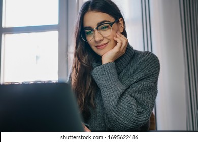 Happy young woman having online video call via laptop computer while working remotely from home, Beautiful hispanic female teacher doing video meetings with screen sharing or webinar on computer 