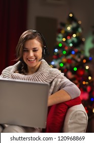 Happy Young Woman Having Video Chat With Family In Front Of Christmas Tree